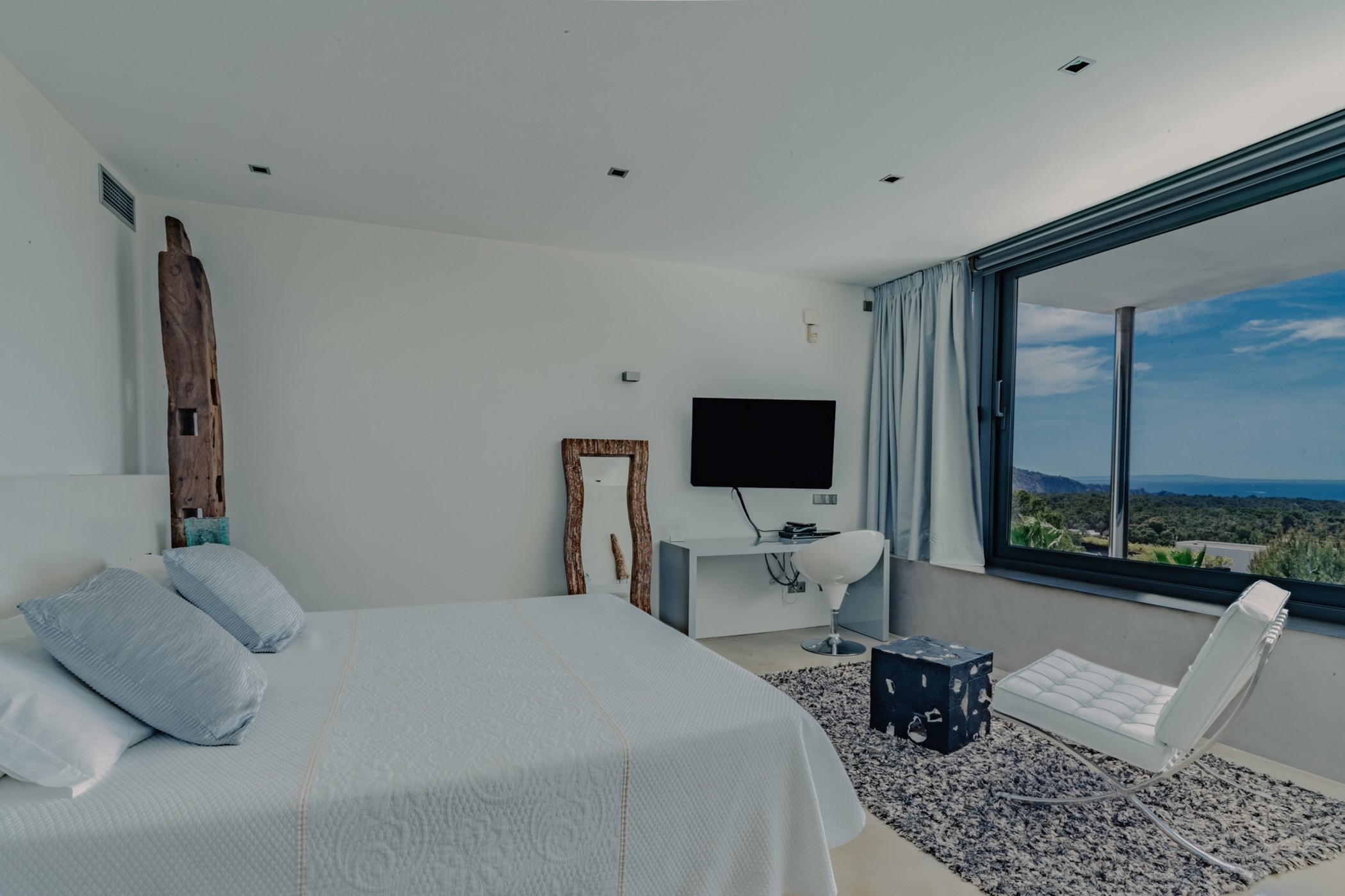 Bright bedroom with a double bed, flat screen television and large sea-view window.