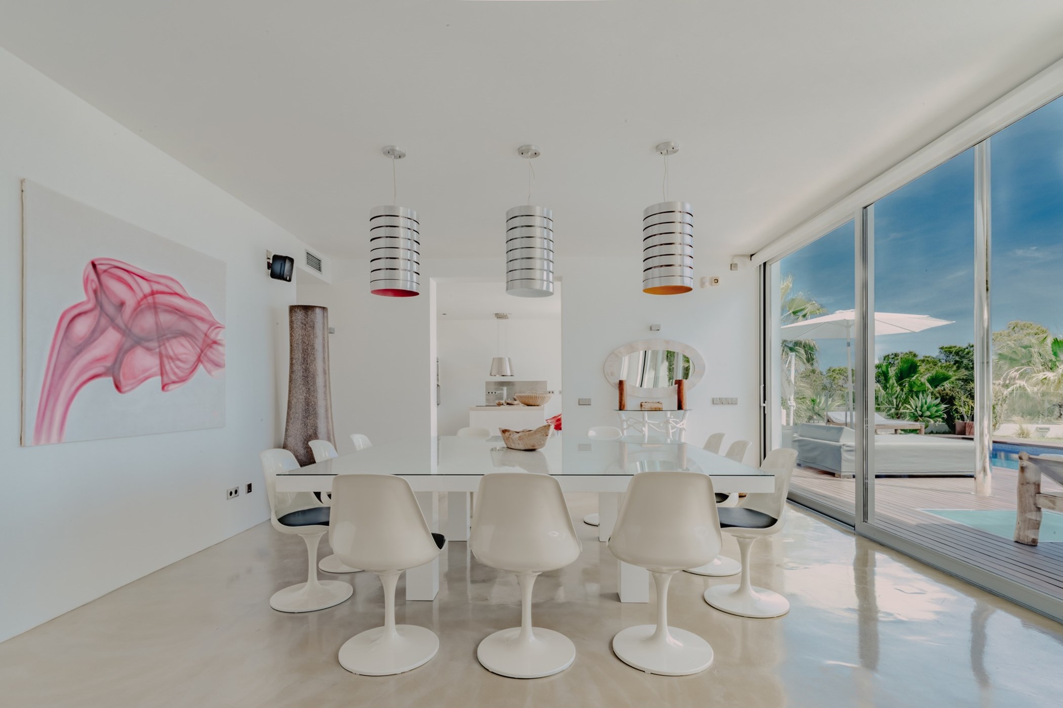 Minimalist dining room with a large white table, retro chairs and sliding doors.
