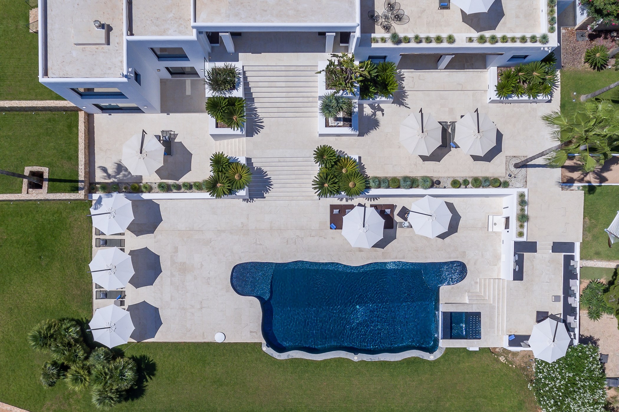 Top-down view of the dark blue swimming pool, white parasols and sun loungers