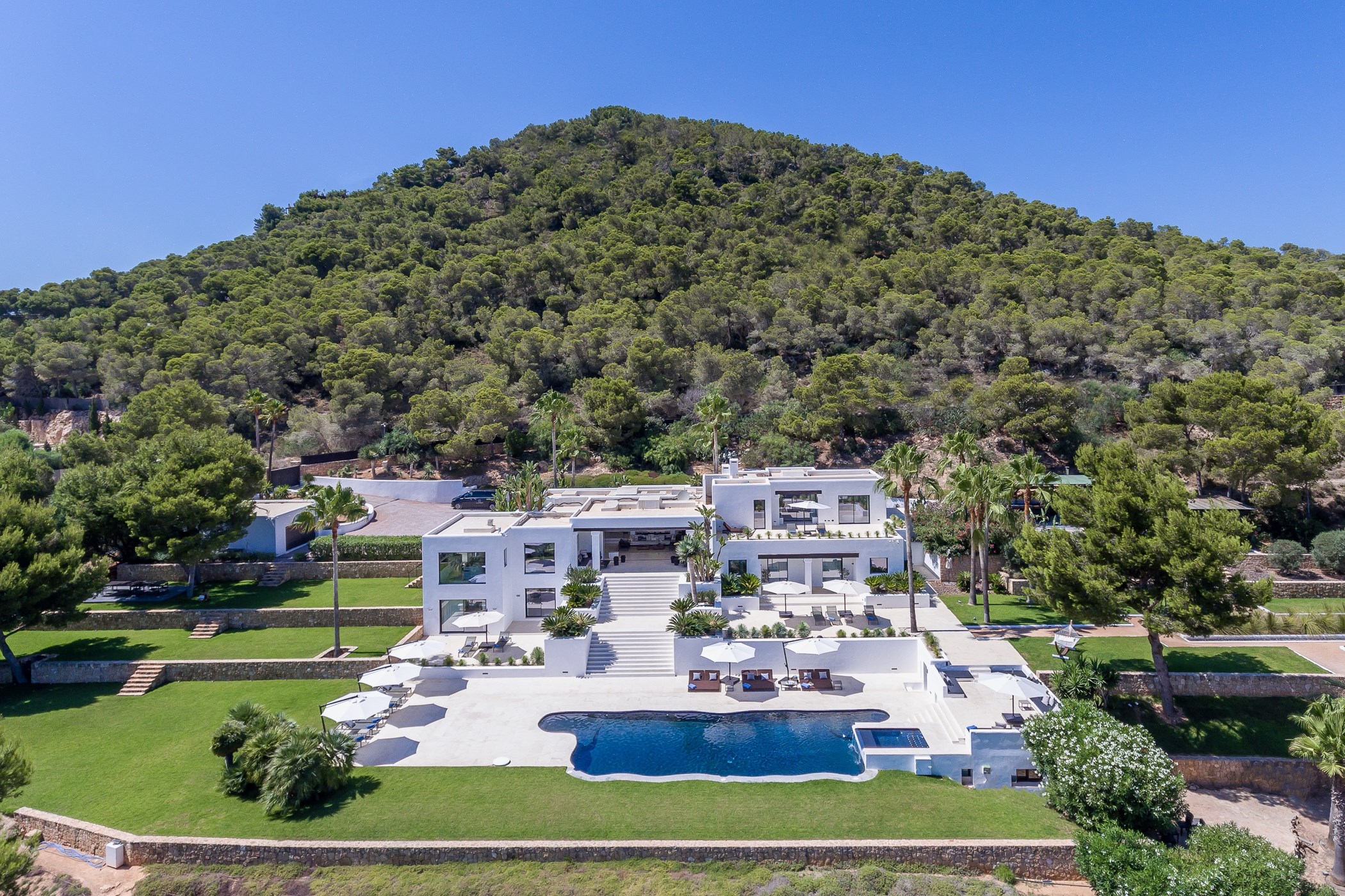 Wide view of the modern white villa exterior, terraced lawns and swimming pool