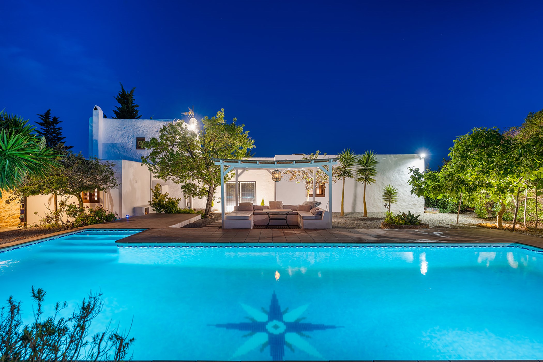 Nighttime view of the swimming pool, terrace, and the villa's covered outdoor lounge.