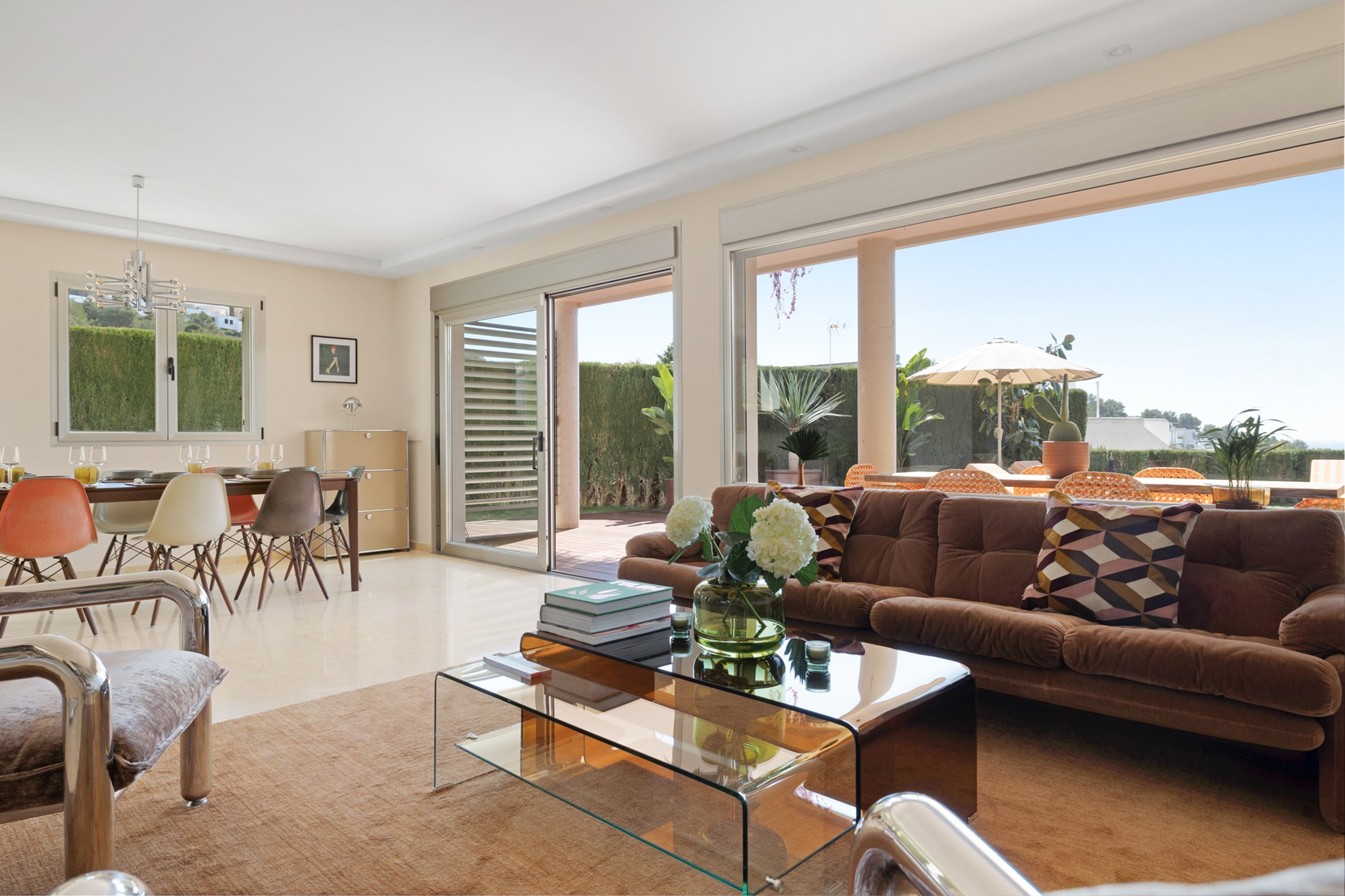 Bright living room with a brown velvet sofa, dining table, and large sliding doors