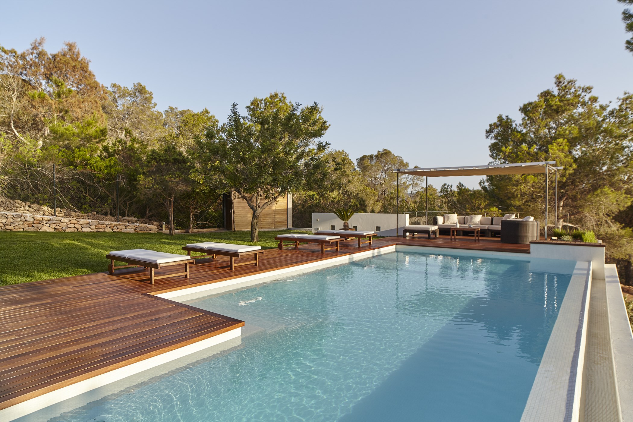 Swimming pool with Roman steps, wooden decking, lawn, and an outdoor seating pergola.