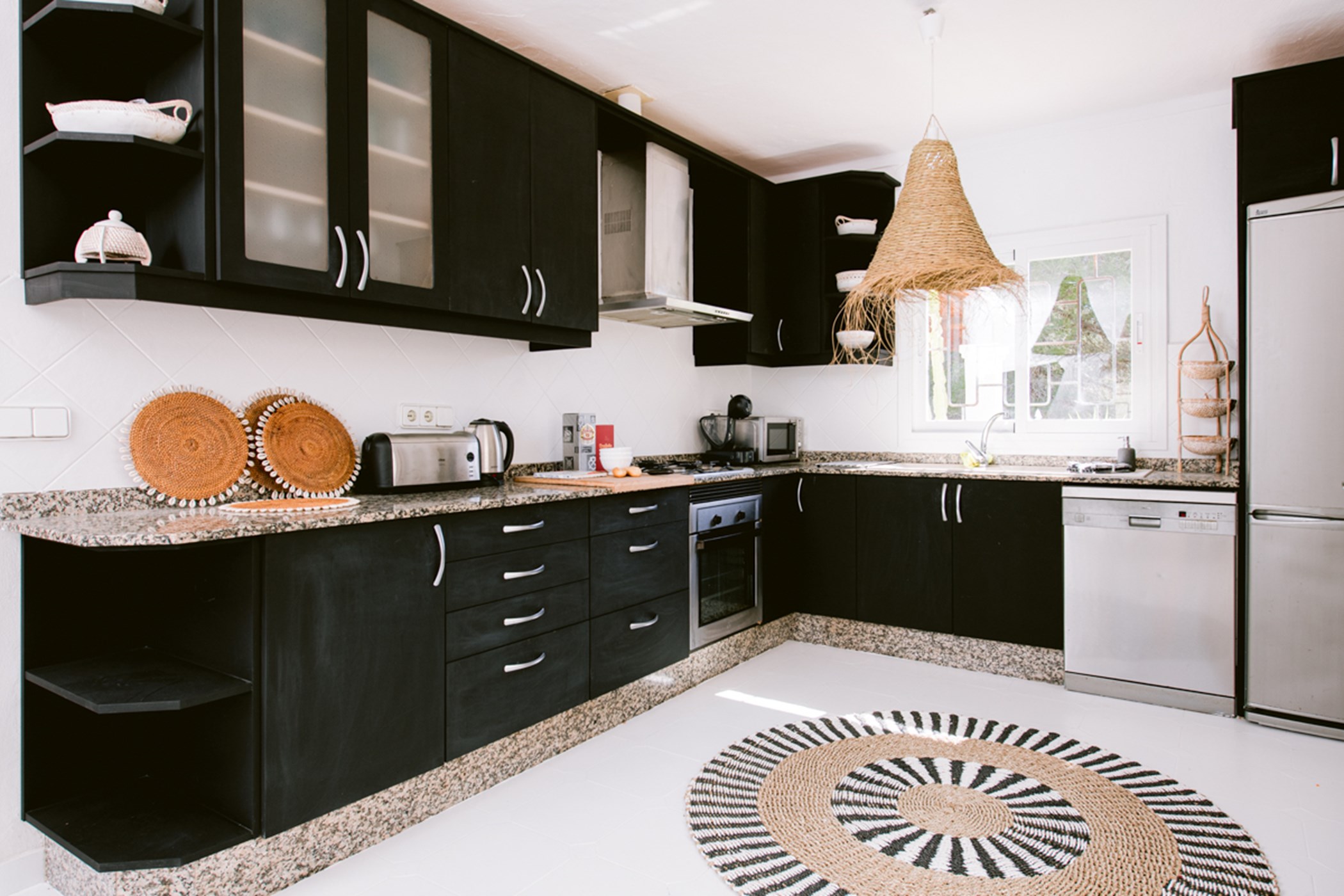 Fully fitted kitchen with black cabinetry, a patterned circular rug, and a woven lampshade