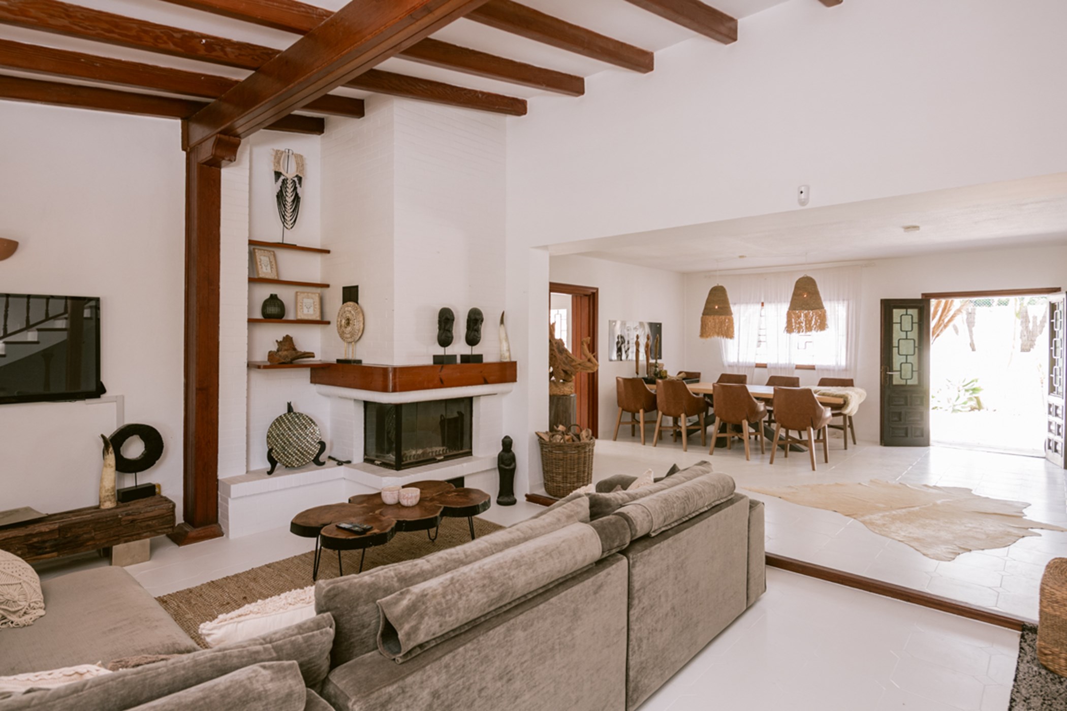 Open-plan living room with grey sofas, a corner fireplace, and a dining table